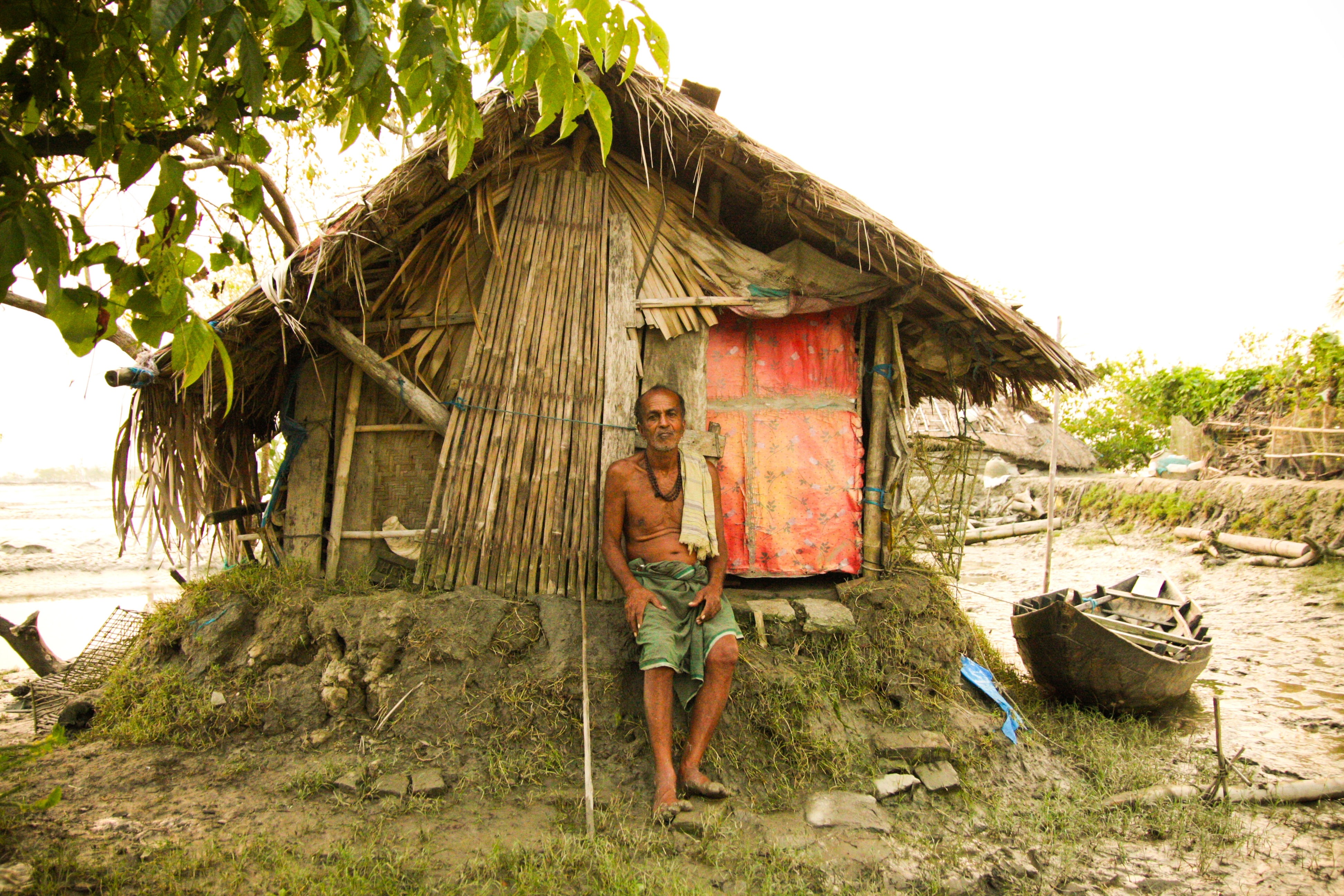 Man at riverside home Bangladesh